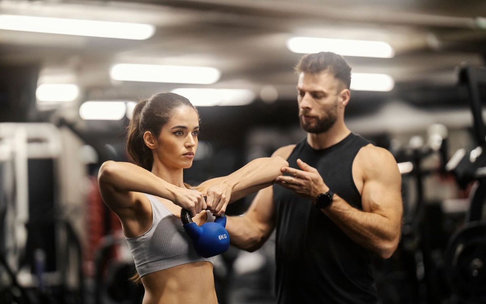 Coach correcting a member’s kettlebell position