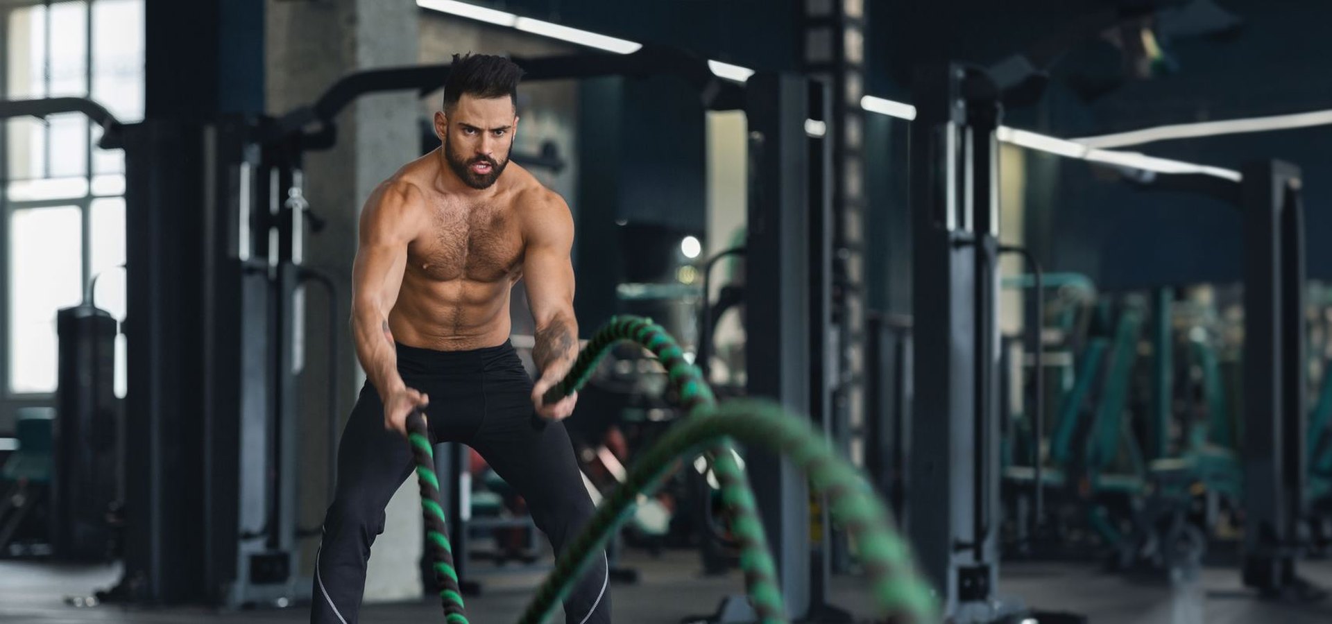 Athlete slamming battle ropes in a dark gym