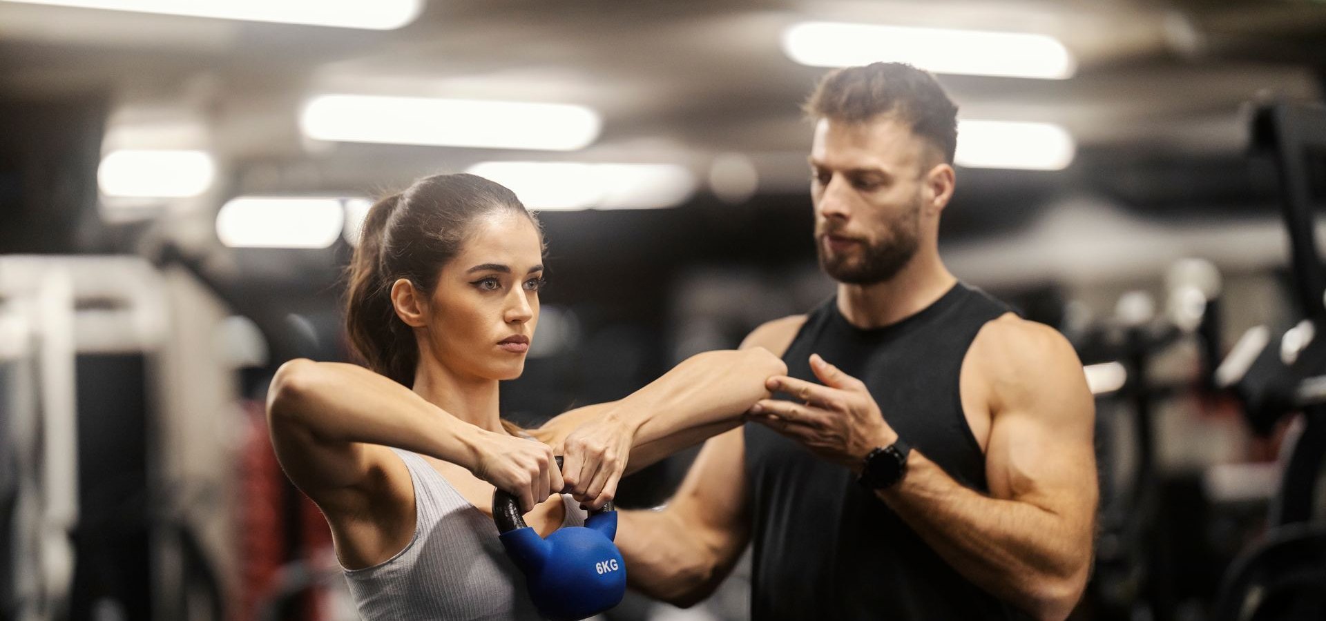 Coach correcting a member’s kettlebell form