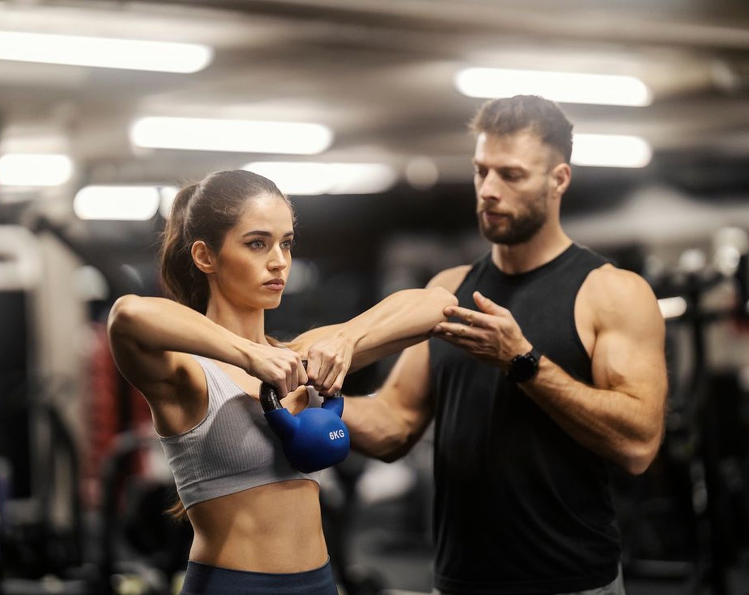 Coach guiding a member through a kettlebell exercise