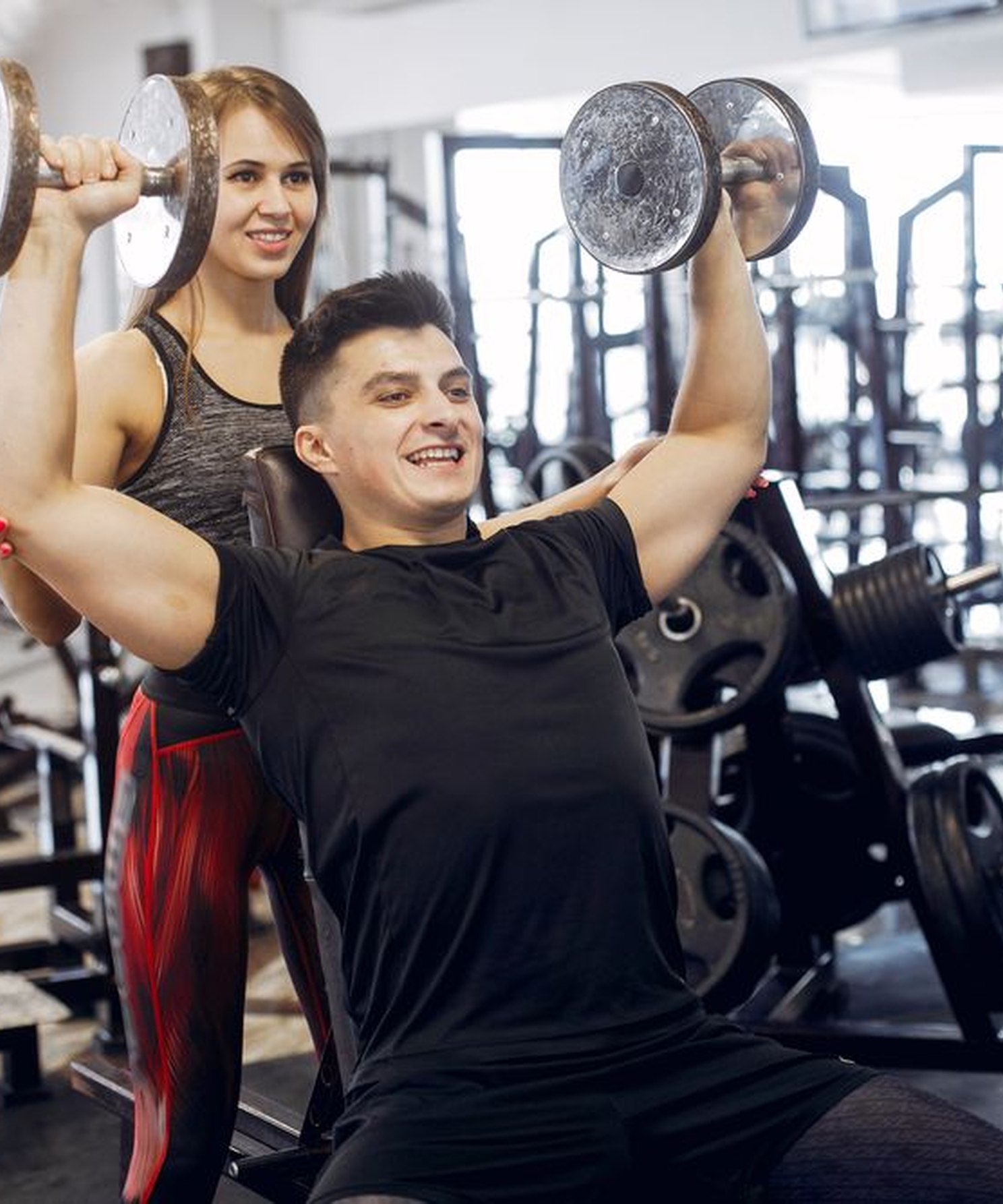 Trainer spotting a member during a dumbbell press